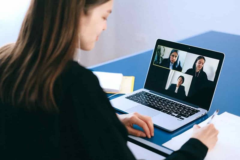 Person in a professional workspace during a video call on a laptop.